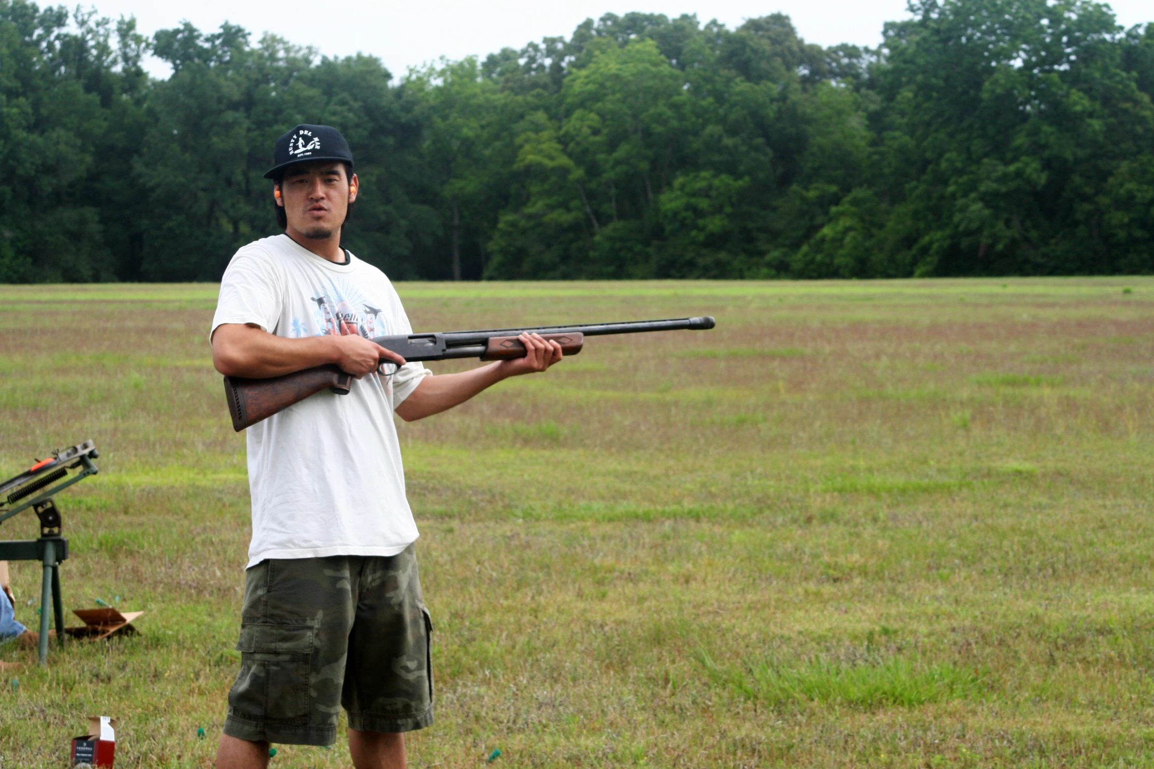 a man standing in the grass holding a gun