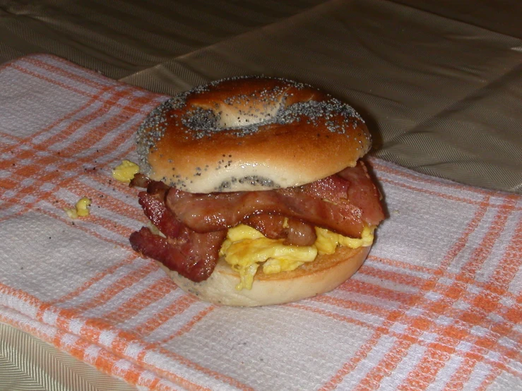 a close up of a bagel that has bacon and eggs on it