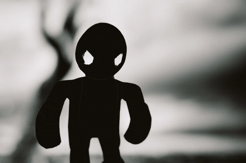 a silhouette of an alien standing near a creepy figure