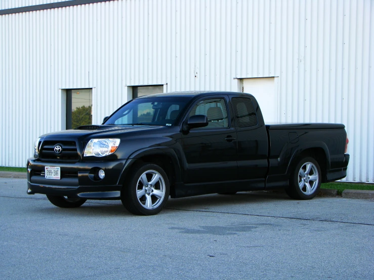 a black truck is parked in front of a white wall