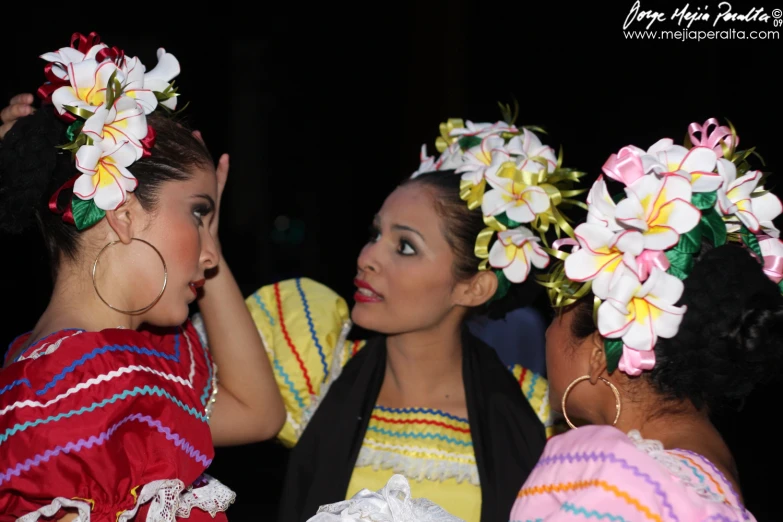 two young women wearing colorful outfits with flowers in their hair