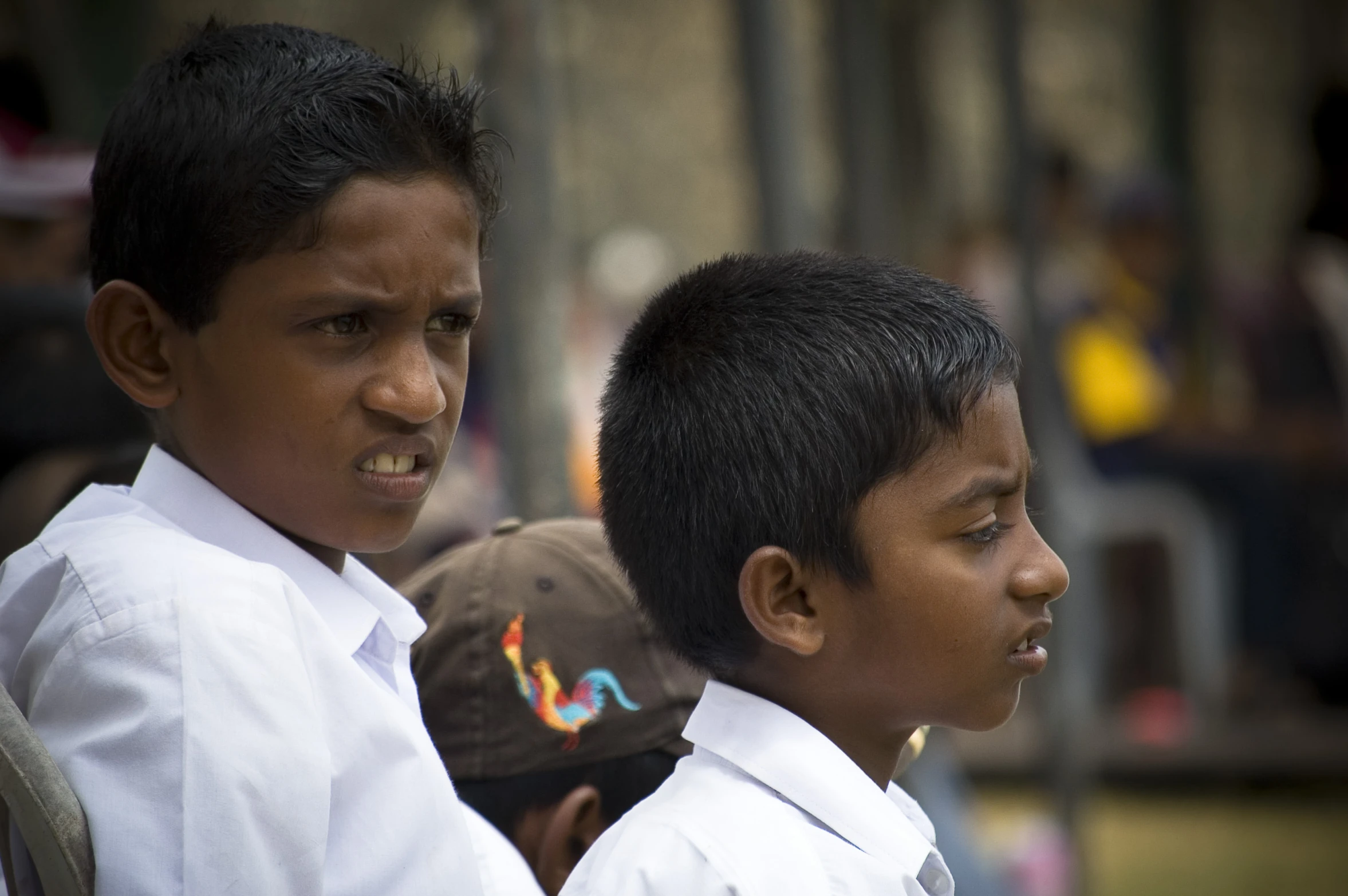 two small boys in a line and one is looking away