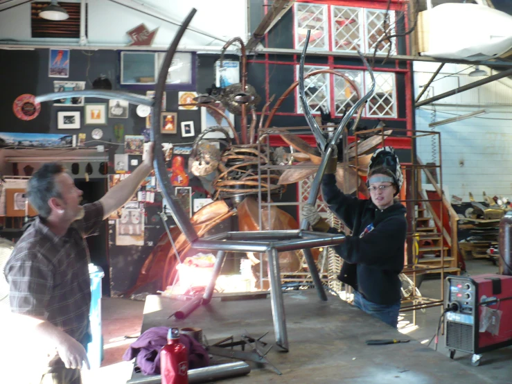 two men working on a sculpture at a shop