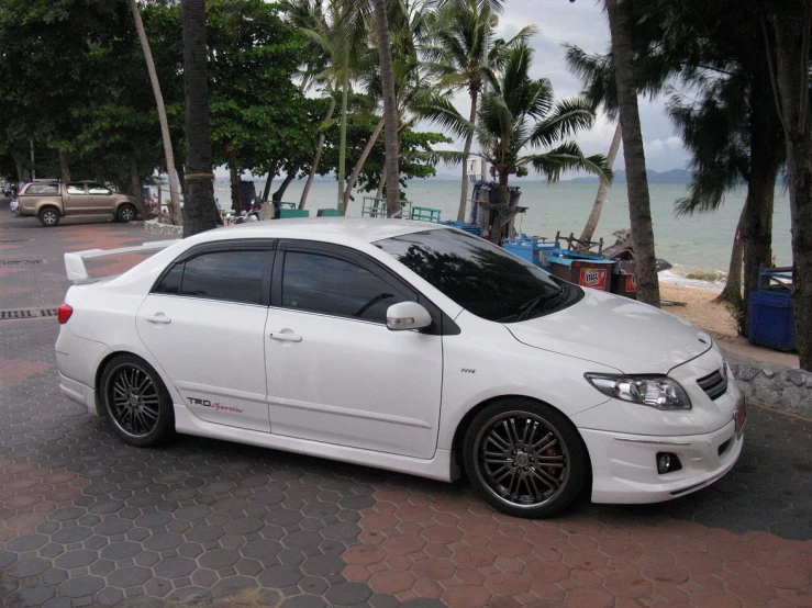 the white car is parked along side of the ocean