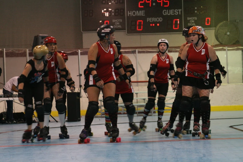 a group of women are on roller blades in an indoor skating rink