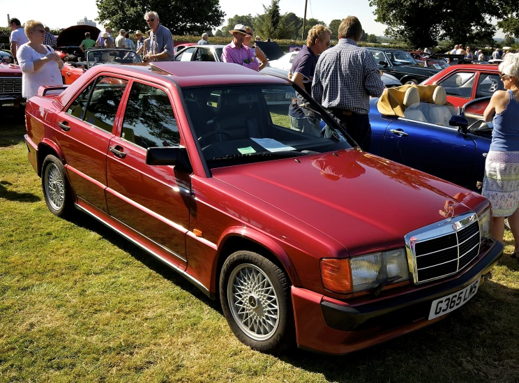 an red car in a grass field with other cars on it