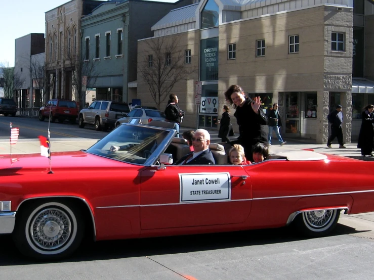 a group of people sitting on top of a red convertible