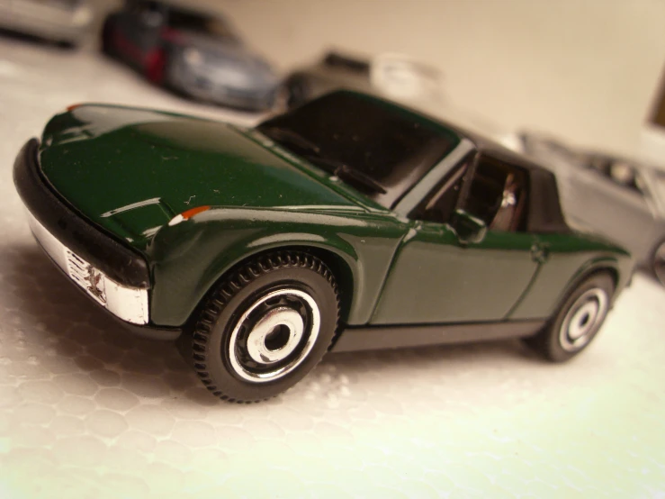 small model green sports car on table with other toy cars in background