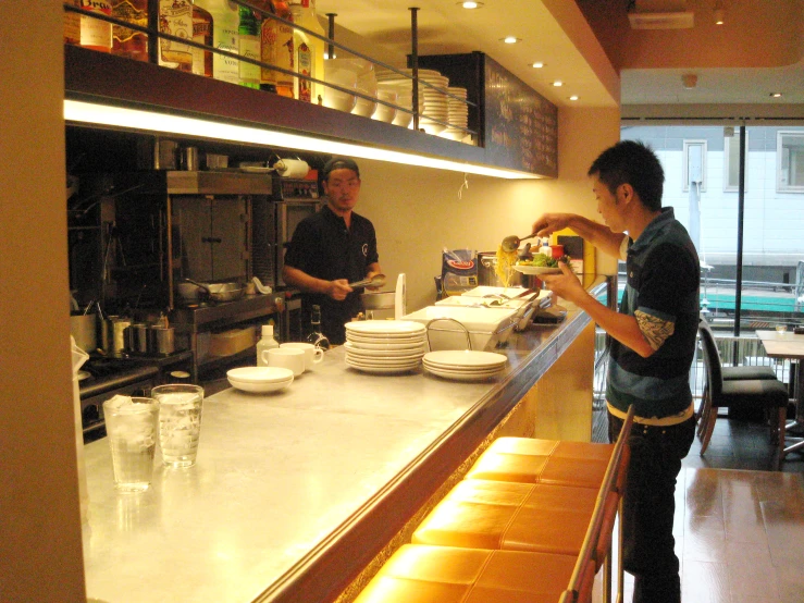 two men are working behind the counter preparing food