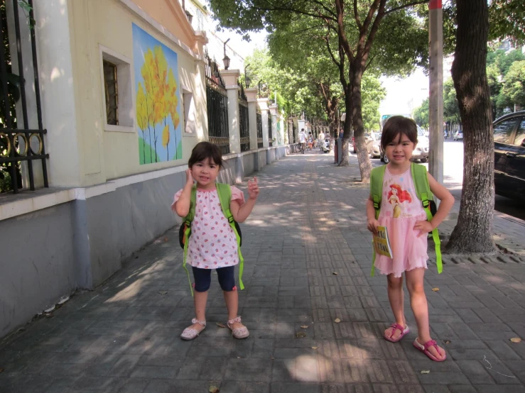 two little girls in colorful dress walking down a street