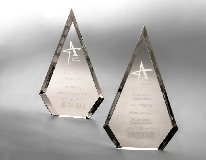 a clear, award winning trophy sitting in front of a gray background