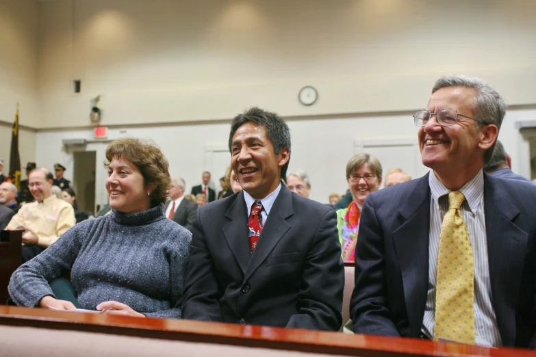 a group of people in a courtroom sitting and smiling