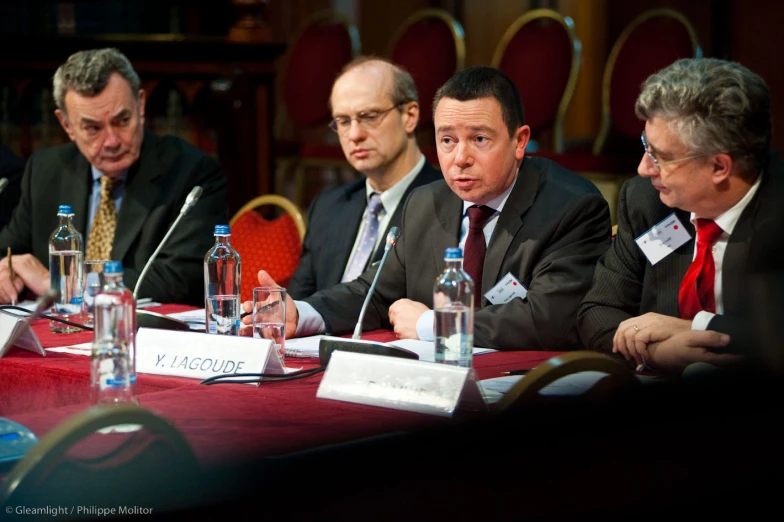 men in business suits sitting at a long table