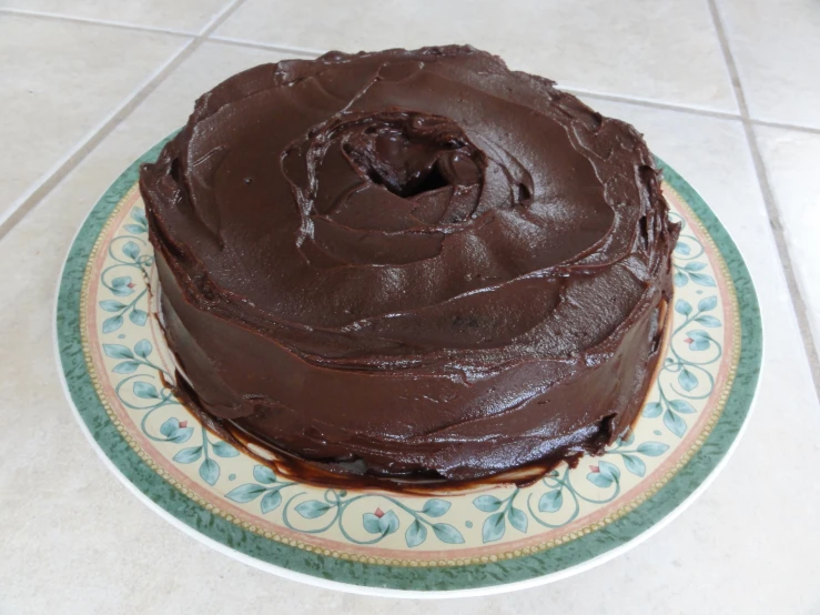 a large chocolate cake with icing on a plate