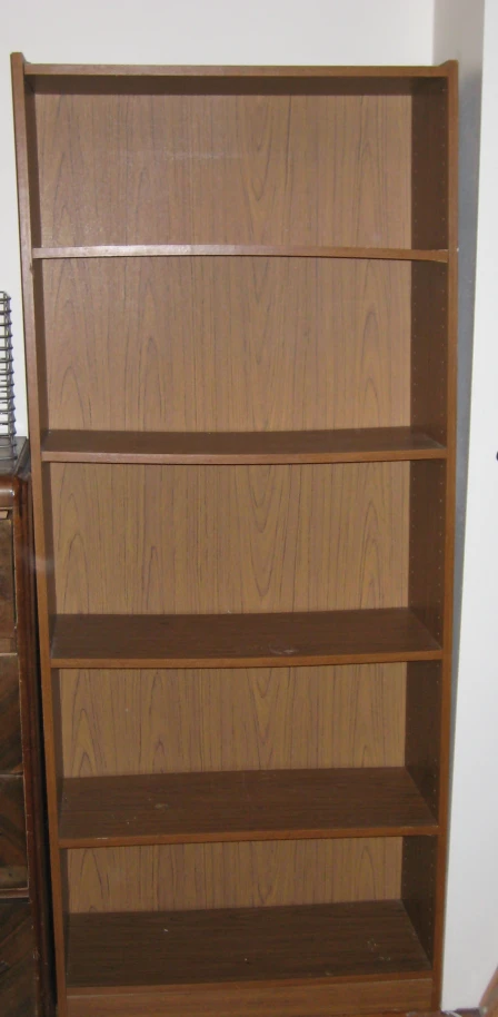 an empty bookcase next to a brown dresser