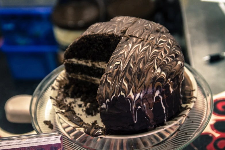 a chocolate cake with a slice cut out and on a clear glass platter