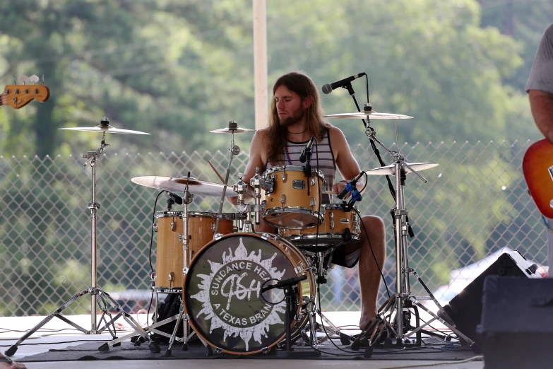 a man sits on a stage with his drums