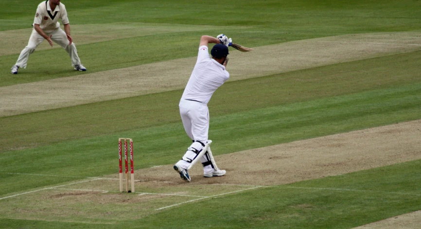 a man reaching up with a bat at the cricket field