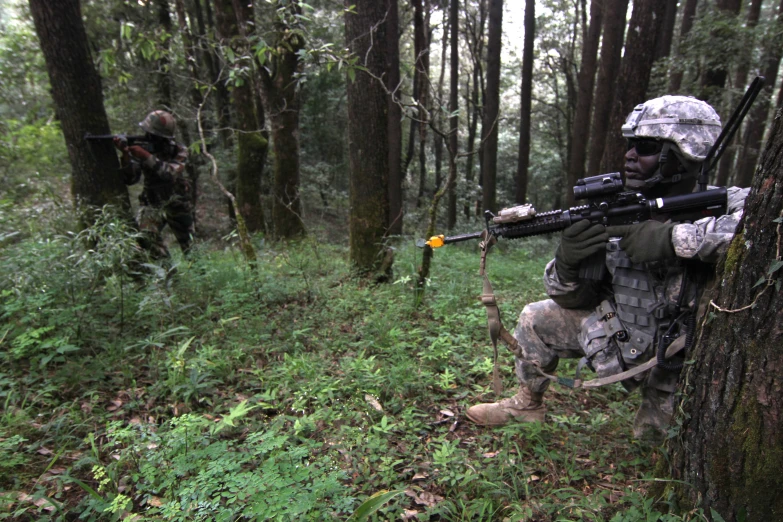 a soldier aiming a gun at another soldier in the forest