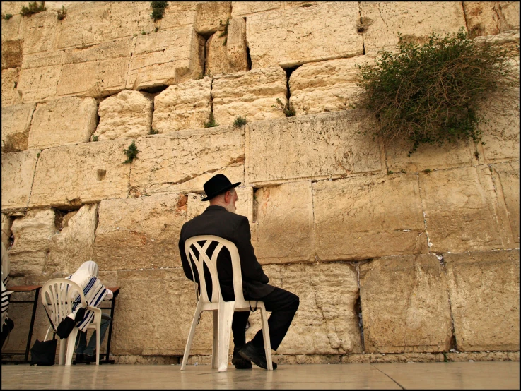 a man sitting alone by a rock wall