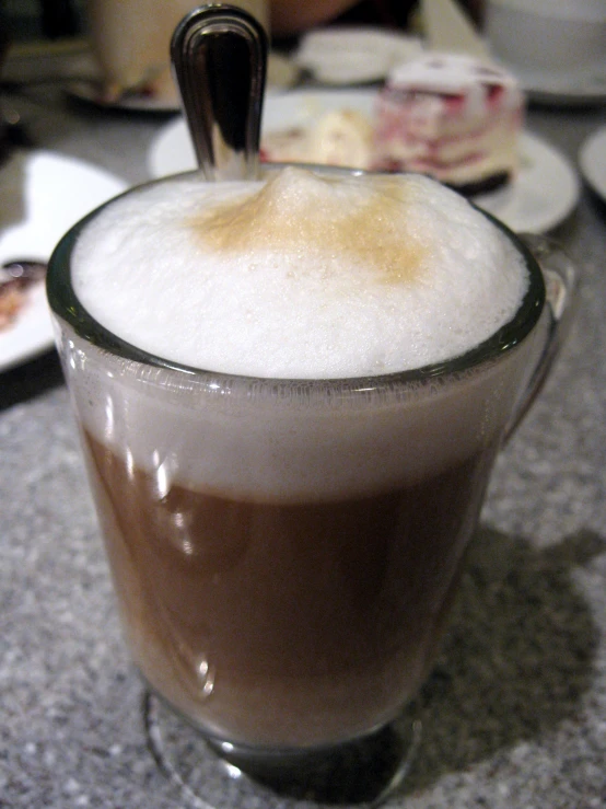 a beverage with brown and white liquid and ice in a glass on the counter