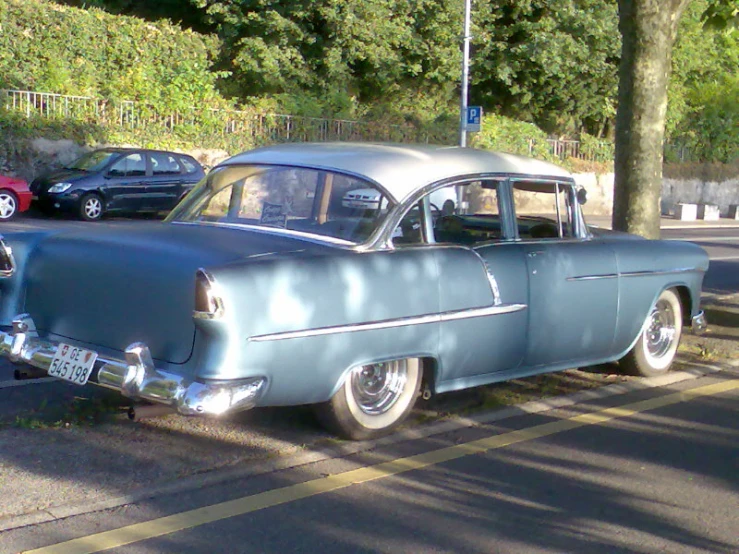 an old blue car parked on the street