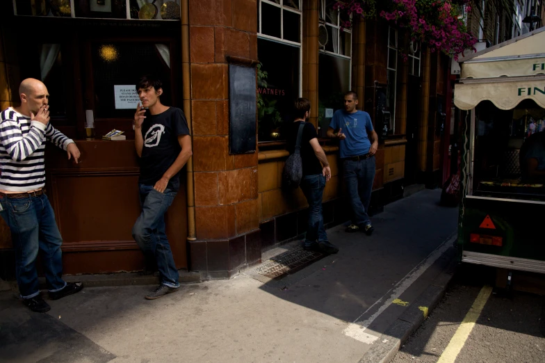 the men are on their cell phones while they are standing outside of the building