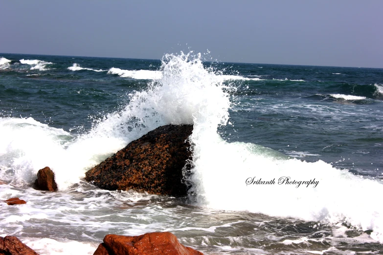 waves hitting rocks in the ocean on a clear day