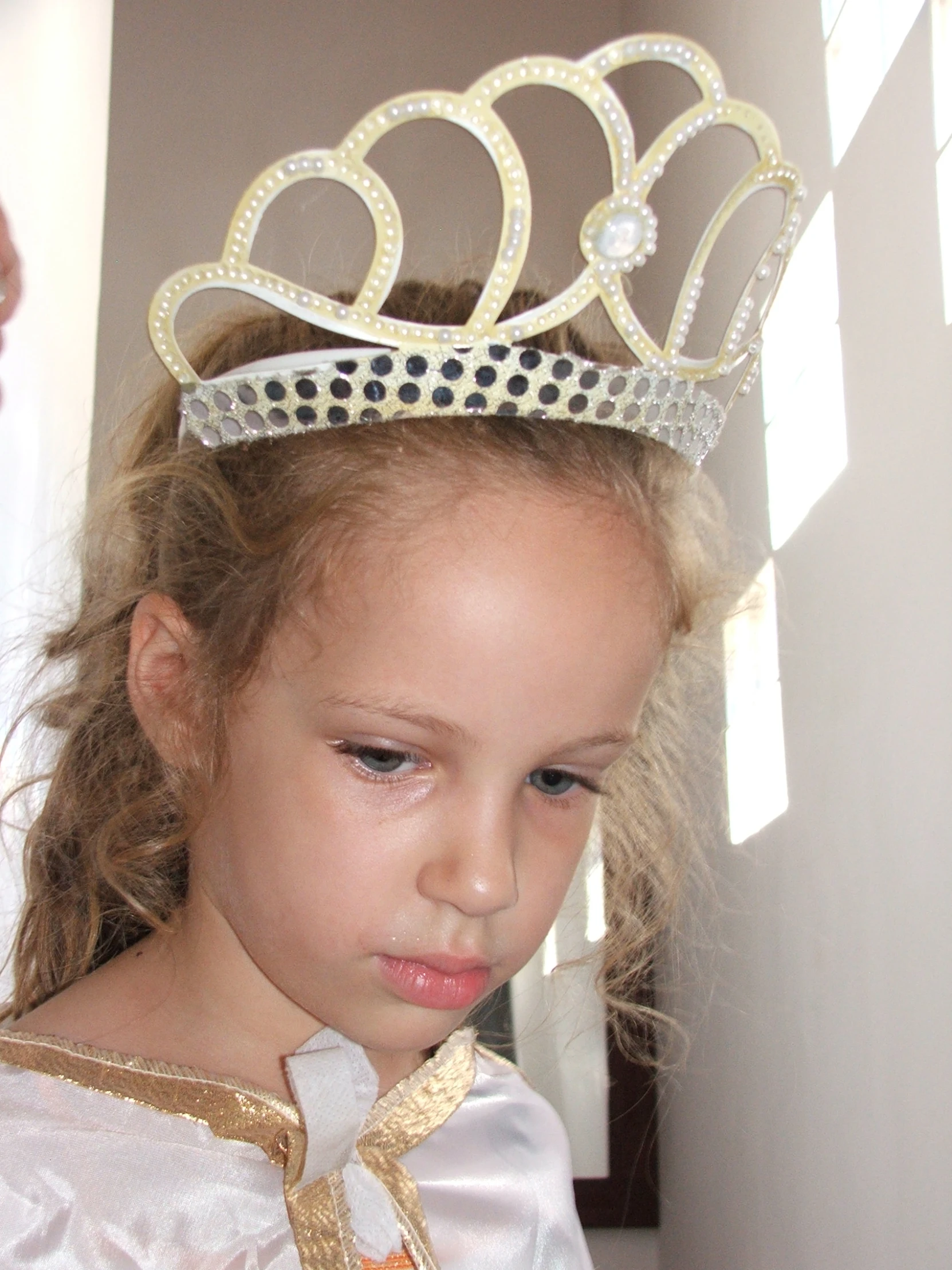 the little girl is wearing a tiara with pearls