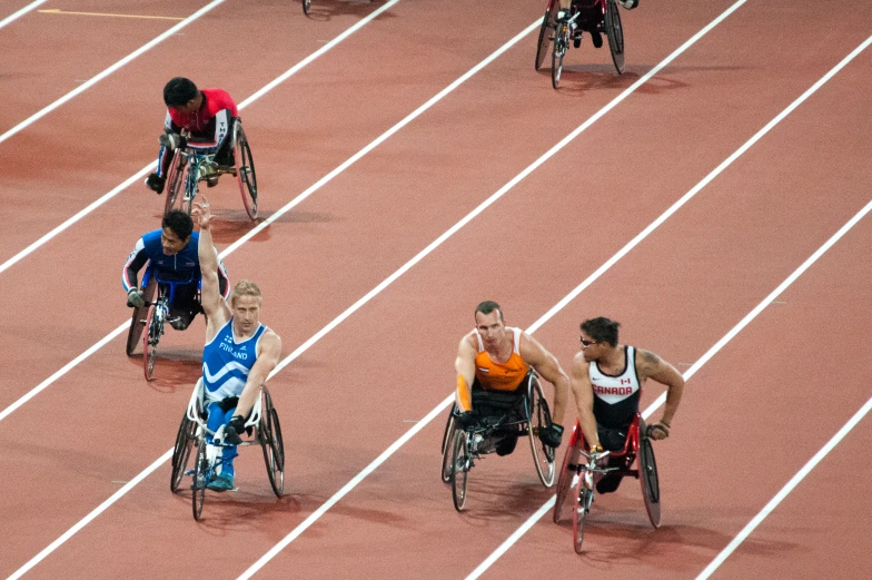 a group of men in wheelchairs race down the track