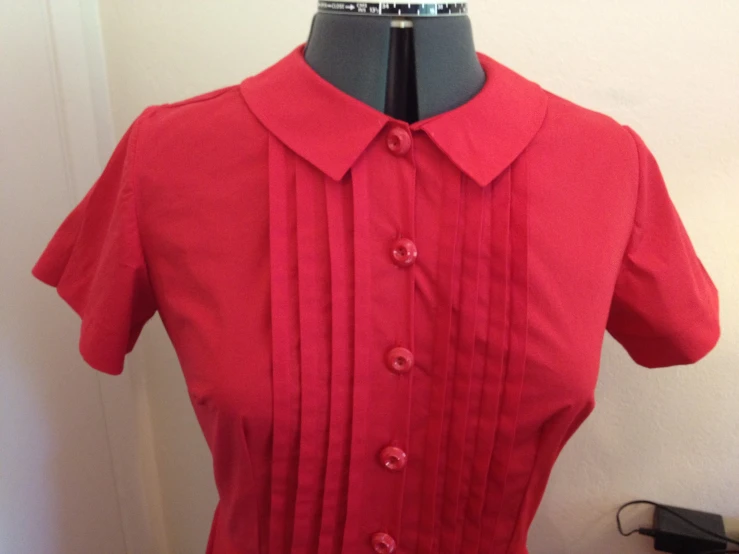 a red dress with ons on the collar is displayed