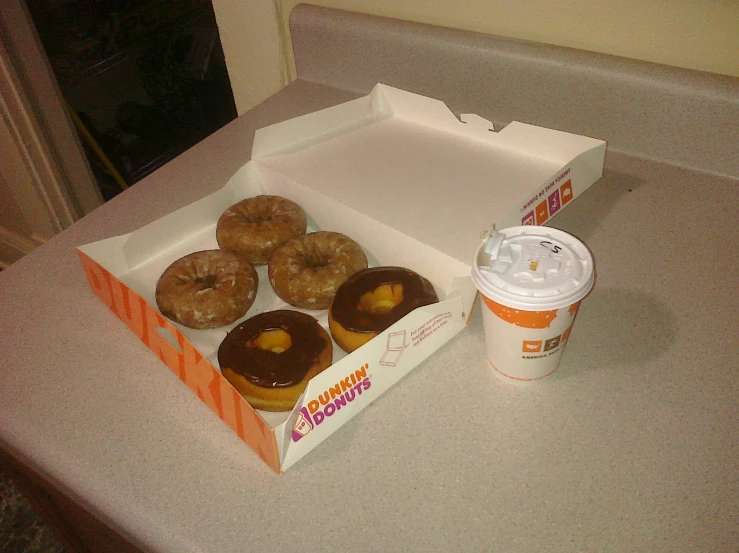 a box of dunkin donuts next to a cup of coffee