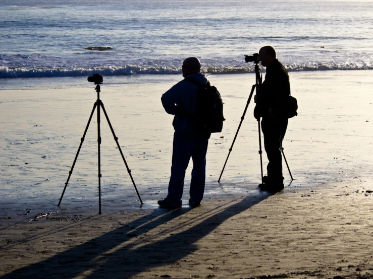 two people holding camera with tripods in front of them