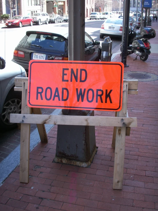 an orange sign on a wood bench saying end road work