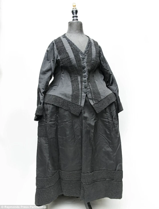 a woman's dress and coat are sitting on a stand