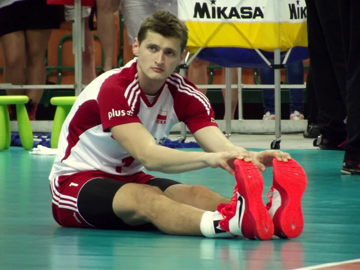 the basketball player is sitting down tying his shoes