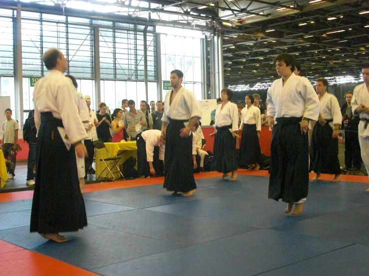 three people standing on a blue mat in a martial competition