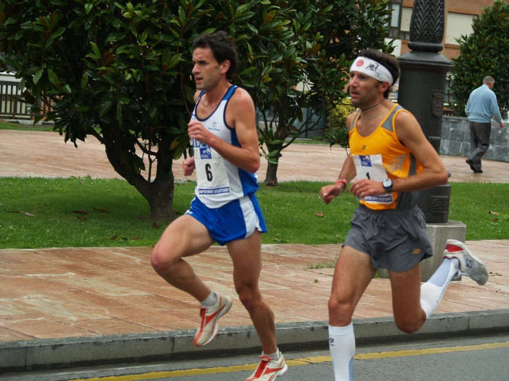 two male runners running down a street in shorts
