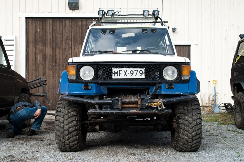 an old blue and white suv with the hood lifted