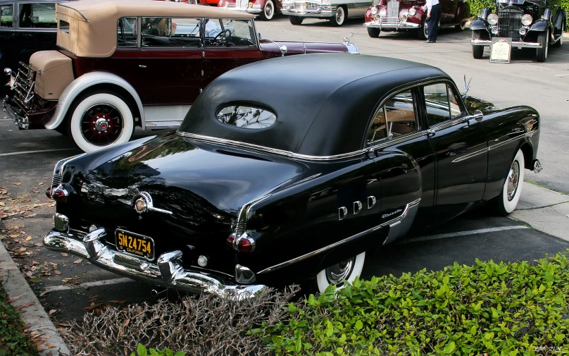 an old model black car parked next to another old model