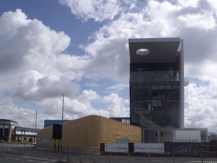 clouds and a building along a road with fencing