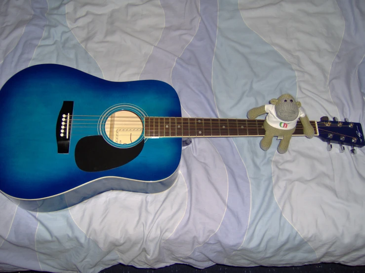 a blue guitar sitting on top of a bed