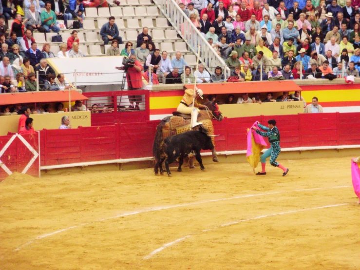 the bull is being attacked by two men on their horses