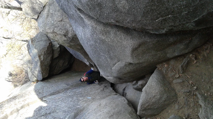 the man is climbing up a boulder formation