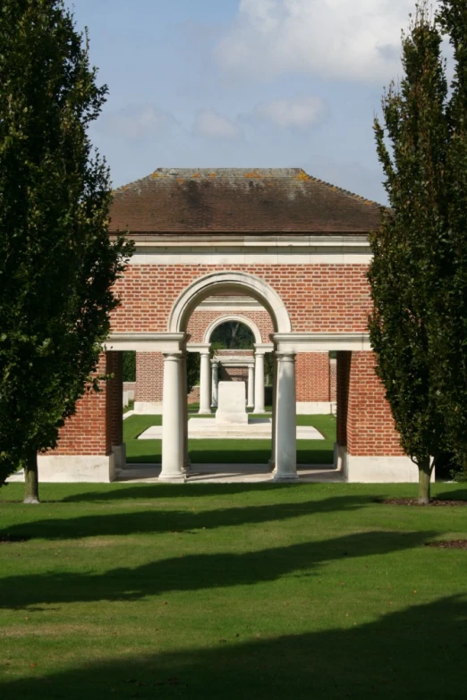 a red brick building with arches between two trees