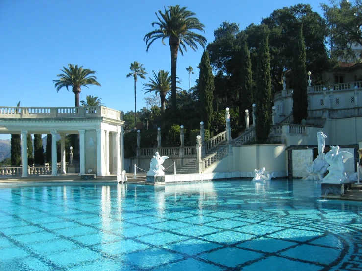 the blue swimming pool is lined with sculptures