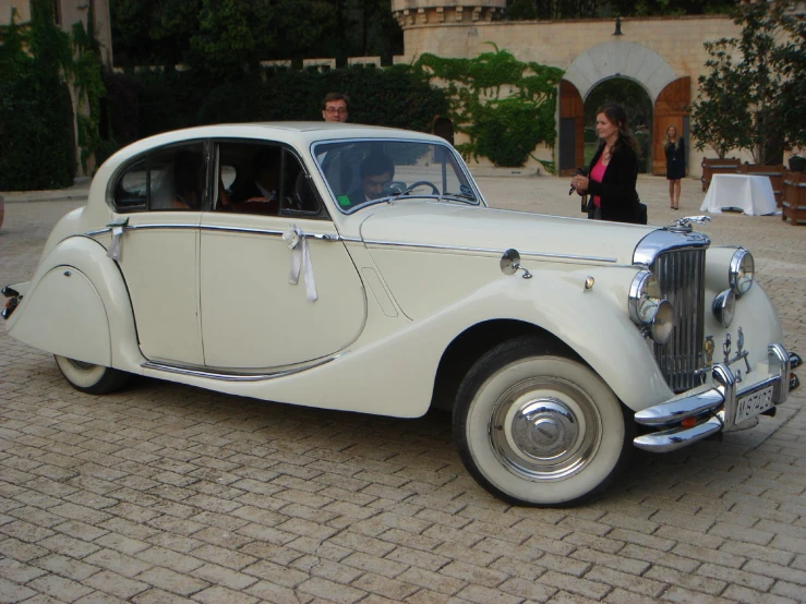 an old white car is parked on a brick surface