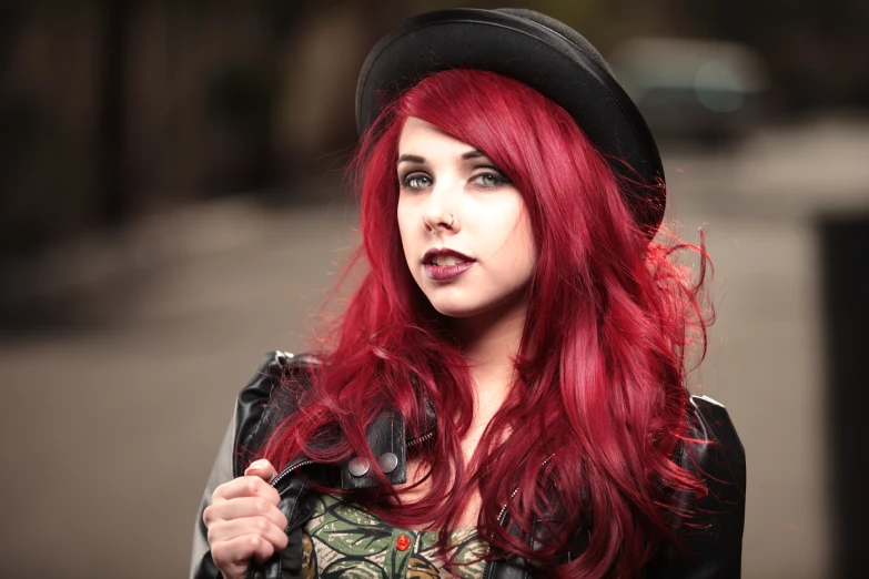 a young woman with red hair is wearing a fedora and a leather jacket