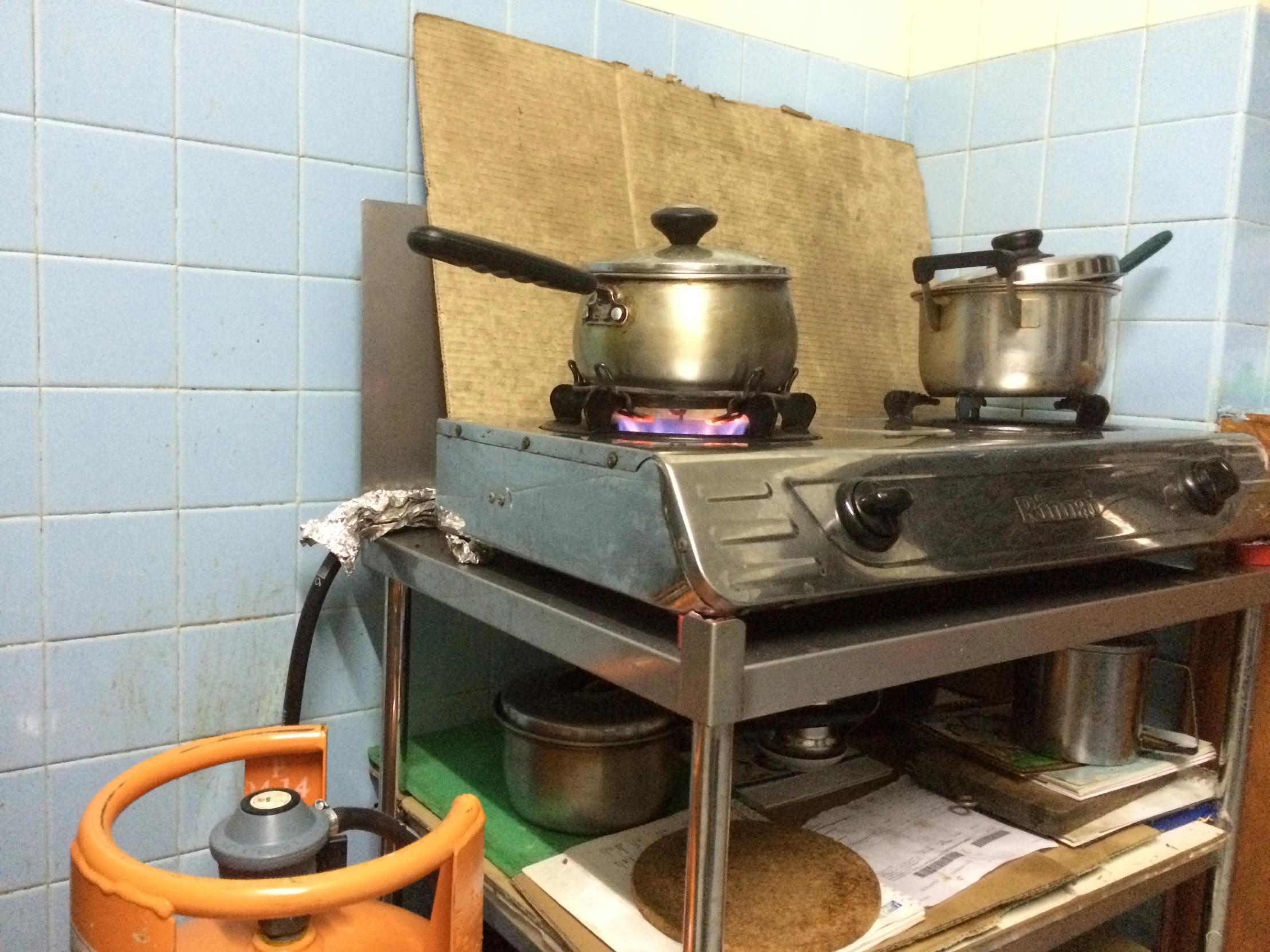 kitchen stove in blue tiled room with metal rack