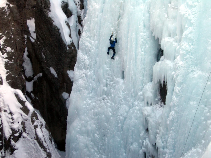 a man is descending up the side of an ice climbing